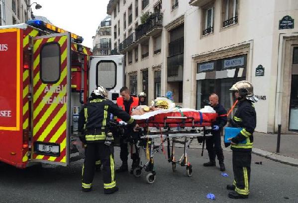Firefighters carry an injured man on a stretcher in front of the offices of the French satirical newspaper Charlie Hebdo in Paris on January 7, 2015. (Xinhua/AFP Photo)