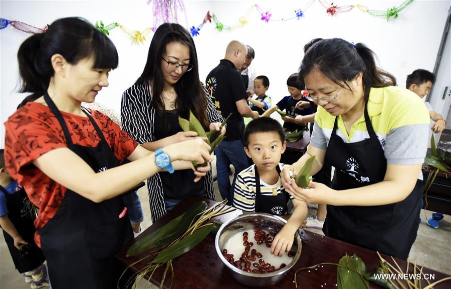 Residents make traditional zongzi, pyramid-shaped dumplings made of glutinous rice and wrapped in bamboo or reed leaves, during a community event to celebrate the upcoming Dragon Boat Festival in Beijing, capital of China, June 4, 2016.
