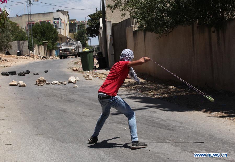 A Palestinian protester hurl stones at an Israeli soldier during clashes after a protest against the expanding of Jewish settlements in a village near the West Bank city of Nablus, on June 10, 2016.