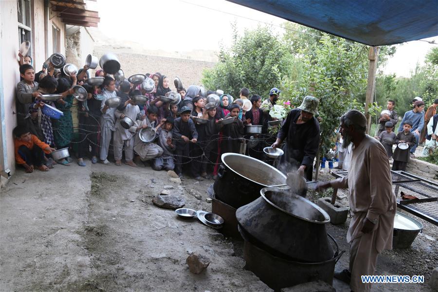 An Afghan man distributes food to children during the holy month of Ramadan in Ghazni province, Afghanistan, June 10, 2016. 