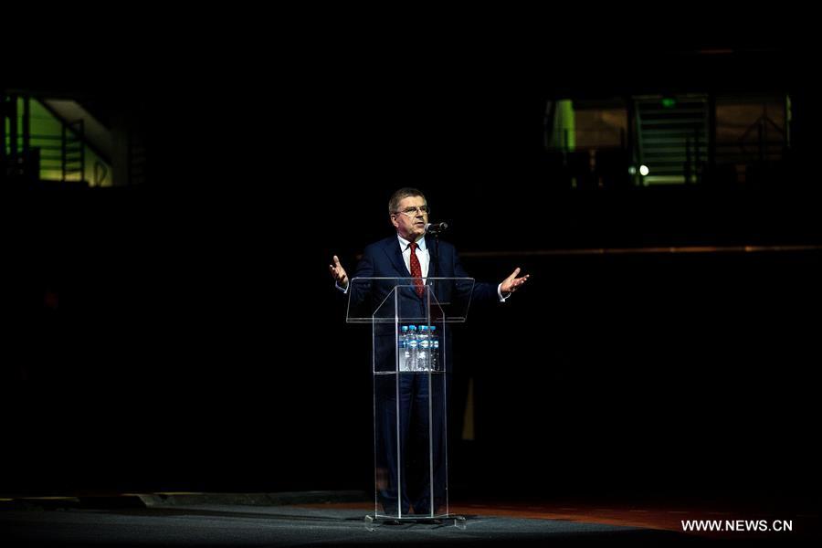 President of the International Olympic Committee (IOC) Thomas Bach delivers a speech as the slogan of the Rio 2016 'A new world' is shown on the screen at the unveiling ceremony held at the Future Arena in the Barra Olympic Park in Rio de Janeiro, Brazil, on June 14, 2016.