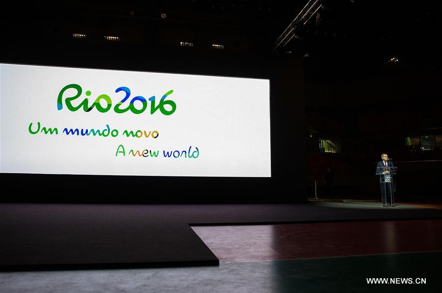 President of the International Olympic Committee (IOC) Thomas Bach delivers a speech as the slogan of the Rio 2016 'A new world' is shown on the screen at the unveiling ceremony held at the Future Arena in the Barra Olympic Park in Rio de Janeiro, Brazil, on June 14, 2016.
