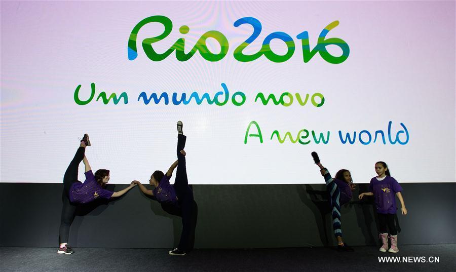 Local children pose in front of the screen displaying the slogan of the Rio 2016 'A new world' after the unveiling ceremony held at the Future Arena in the Barra Olympic Park in Rio de Janeiro, Brazil, on June 14, 2016.