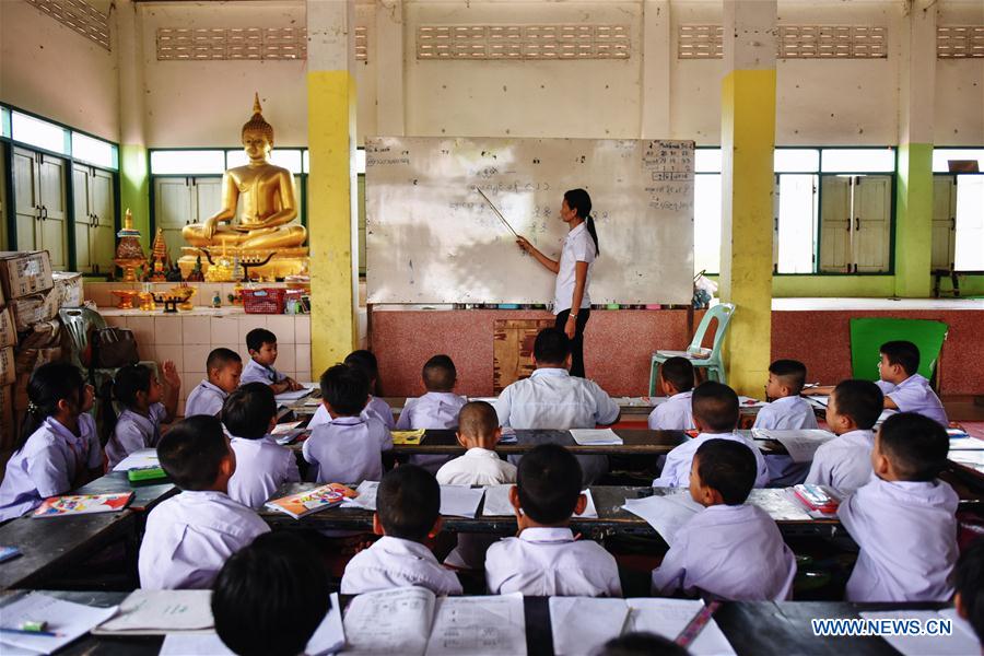 A teacher (1st L) revises homework for students at a school dedicated for the children of Myanmar migrant workers set inside Wat Tepnorrarat in Mahachai of Samut Sakhon Province, central Thailand, June 16, 2016. 