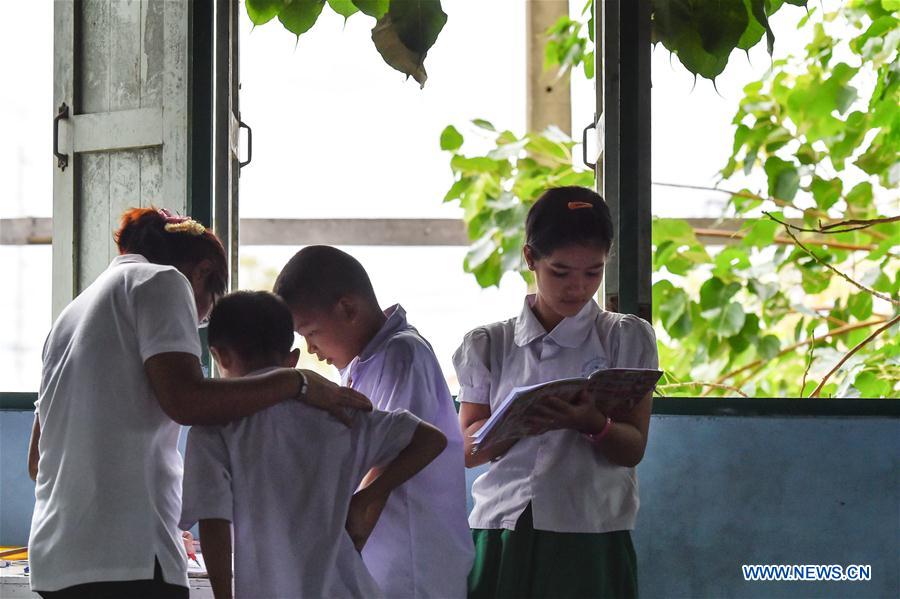 A teacher (1st L) revises homework for students at a school dedicated for the children of Myanmar migrant workers set inside Wat Tepnorrarat in Mahachai of Samut Sakhon Province, central Thailand, June 16, 2016. 