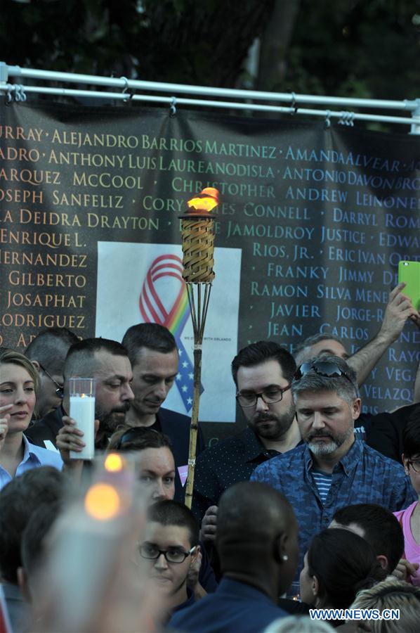 People hold candles and a torch to pay tribute to Orlando nightclub shooting victims, in downtown Montreal, Canada, on June 16, 2016.