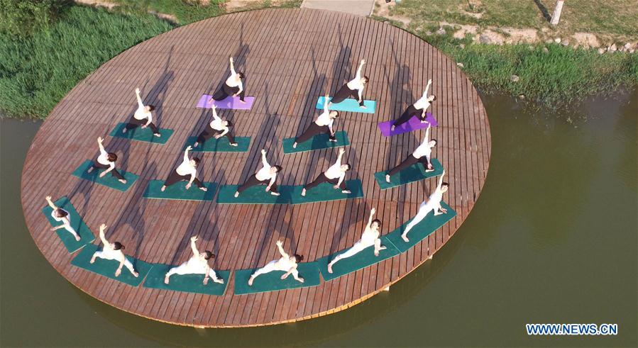 People practise yoga at the Longquan Lake Park in Wuzhi County of Jiaozuo, central China's Henan Province, June 18, 2016. 