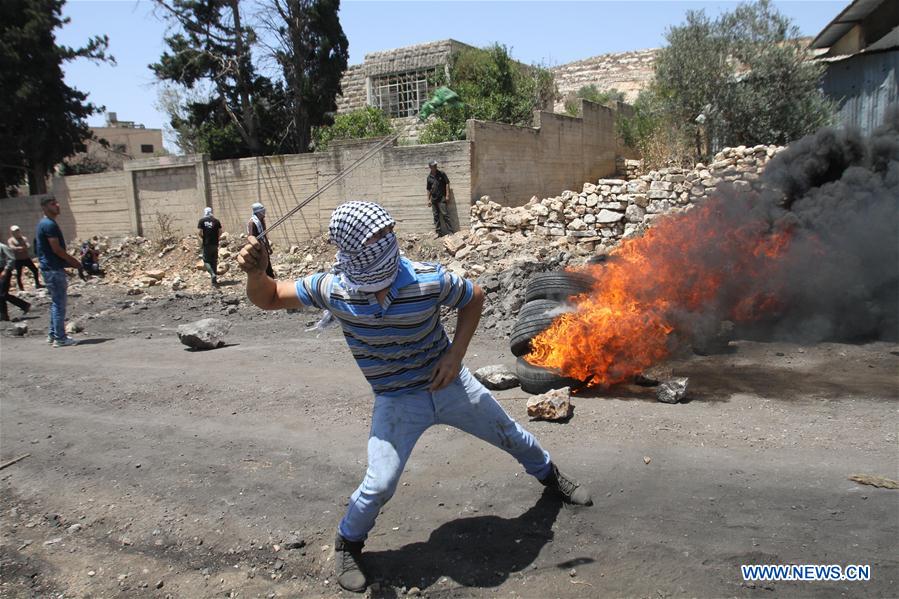 A Palestinian protester hurls stones at an Israeli soldier during clashes after a protest against the expanding of Jewish settlements in Kufr Qadoom village near the West Bank city of Nablus on June 24, 2016.