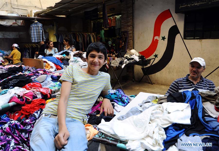 A Syrian vendor leans on a stall of second-hand clothes in Damascus, capital of Syria, on June 28, 2016. 