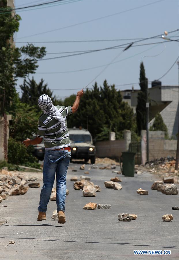 A Palestinian protester hurls stones at an Israeli soldiers during clashes after a protest against the expanding of Jewish settlements in Kufr Qadoom village near the West Bank city of Nablus, on July 1, 2016