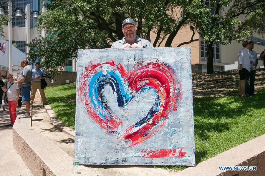 A man holds a heart-shaped painting during a mourning for the police personnel killed by snipers in Dallas, the United States, July 8, 2016.