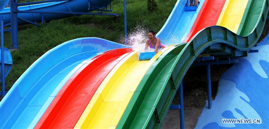 A Nepalese girl slides into a swimming pool at the newly-opened Whoopee Land Amusement and Water Park in Chobhar, on the outskirts of Kathmandu, capital of Nepal, July 10, 2016.