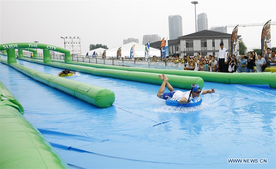 A girl slides down from the water slide at the Slide the City, a water themed fun park for people to pass heated summer, in Shanghai, east China, July 13, 2016.