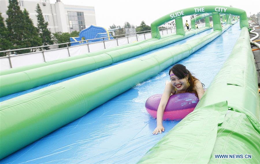 A girl slides down from the water slide at the Slide the City, a water themed fun park for people to pass heated summer, in Shanghai, east China, July 13, 2016.