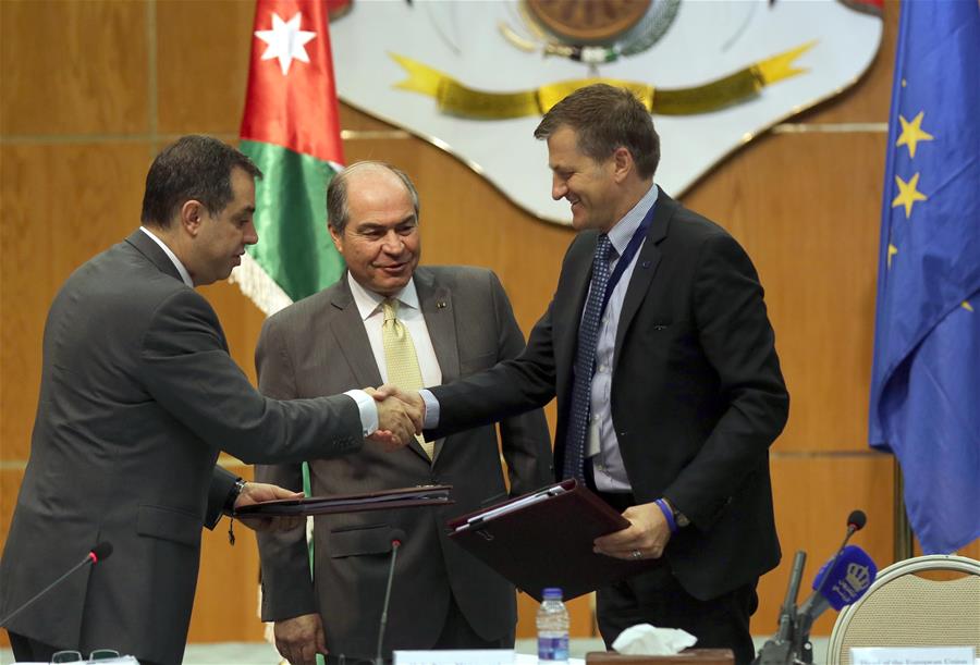 EU Ambassador to Jordan Andrea Matteo Fontana (R) shakes hands with Jordanian Minister of Planning and International Cooperation Emad Fakhoury (L) after signing an agreement, as Jordanian Prime Minister Hani Mulki (C) stands behind, in Amman, Jordan, 20 July 2016. 