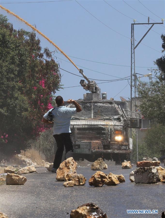  A Palestinian protester hurls a stone at Israeli force during clashes after a protest against the expanding of Jewish settlements in Kufr Qadoom village near the West Bank city of Nablus, on July 22, 2016 