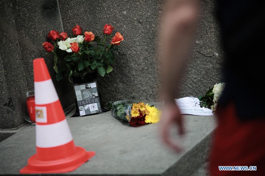 A pedestrian walks past flowers for mourning in front of the representation office of Bavaria in Berlin, capital of Germany, on July 23, 2016.