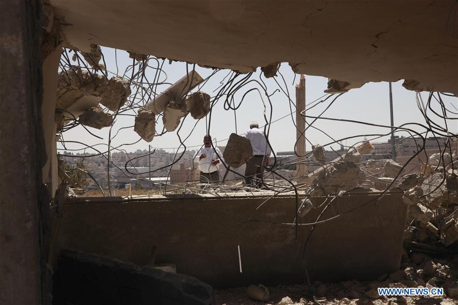 Palestinians stand by the rubble of a house which was demolished by Israeli army bulldozers in the village of Qalandiya, next to Israel's controversial separation barrier, near the West Bank town of Ramallah on July 26, 2016.