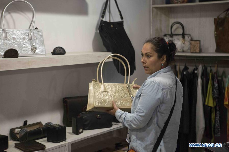 A woman picks up one of the leather goods made by inmates from Mexican prisons at a store in Mexico City, capital of Mexico on July 26, 2016.