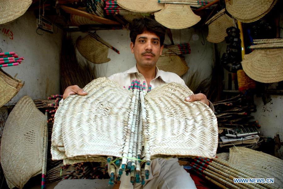A man shows handmade fans at a shop in northwest Pakistan's Peshawar, Aug. 6, 2016.