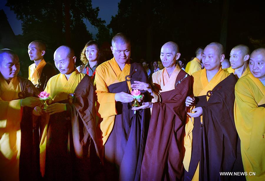 Monks carrying lotus-pattern lamps attend a buddhist ritual at the Shaolin Temple on the Songshan Mountain in Dengfeng City, central China's Henan Province, Aug. 13, 2016.