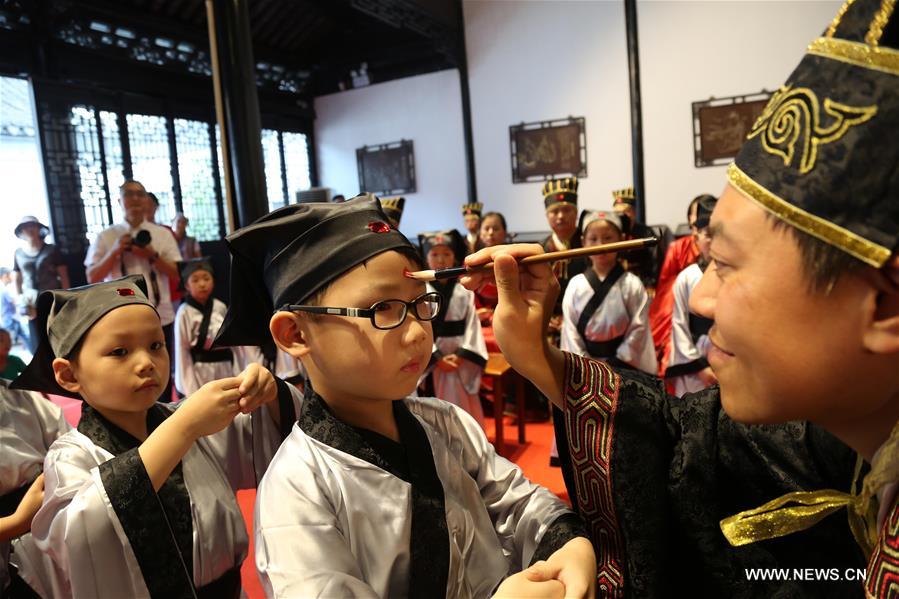 Children recite paragraphs of Standards for Students with their parents during a ceremony to mark the new semester at Donglin Academy in Wuxi, east China's Jiangsu Province, Aug. 27, 2016. 