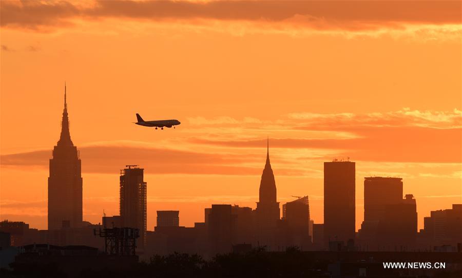 An airplane flies over Manhattan as the sun sets in New York, the United States, Sept. 7, 2016.