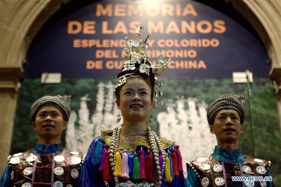 A woman and two men in traditional costumes are highlighted at the opening ceremony of the exhibition 'Memory of the Hand - Splendor and Colorful Heritage of Guizhou' at the National Museum of Cultures in Mexico City, capital of Mexico, Sept. 28, 2016. Embroidered costumes, paper cutting, wooden masks and silver jewelry of the Guizhou province, part of its variety of intangible heritage of China, are displayed during the exhibition at the National Museum Cultures of Mexico. 