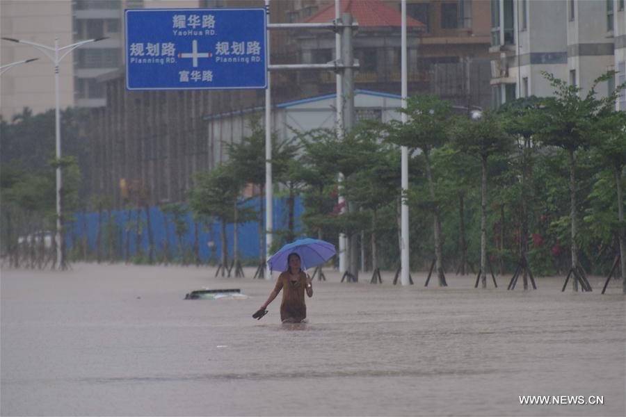 A citizen walks through a waterlogged street in rain-hit Qionghai, south China's Hainan Province, Oct. 13, 2016.