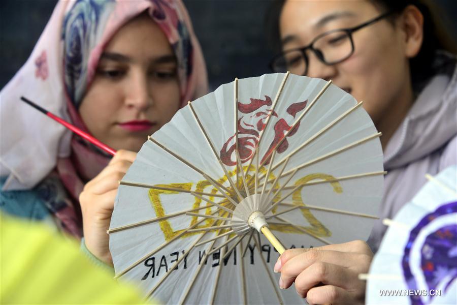 Volunteers from the Academy of Arts of Liaocheng University and students from Jordan and Ethiopia on Sunday painted patterns involving rooster on oil-paper umbrellas to greet the upcoming Chinese lunar New Year of Rooster, which falls on Jan. 28 this year.