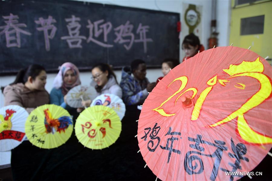 Volunteers from the Academy of Arts of Liaocheng University and students from Jordan and Ethiopia on Sunday painted patterns involving rooster on oil-paper umbrellas to greet the upcoming Chinese lunar New Year of Rooster, which falls on Jan. 28 this year.