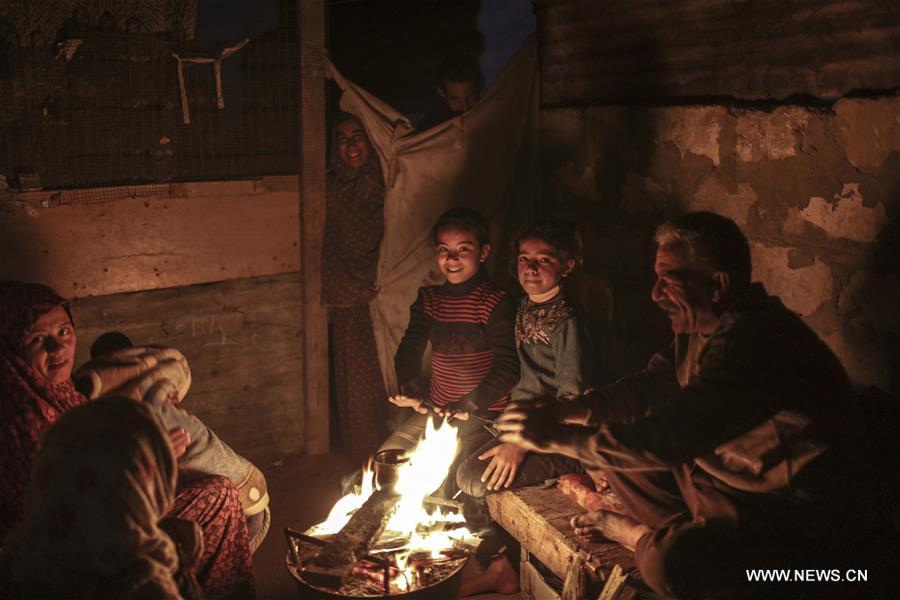 Palestinian refugees warm themselves in front of a fire outside their house during a power outage in Al Zaitun neighbourhood, east of Gaza City, on Jan. 11, 2017. (Xinhua/Wissam Nassar)