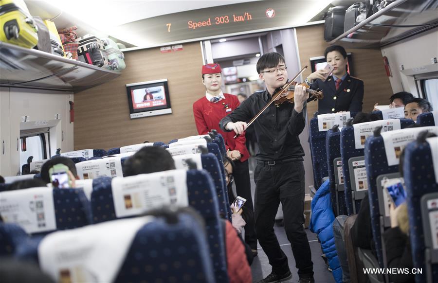 Students from the School of Music of Central China Normal University play violin for passengers on high-speed train G77 from Wuhan, capital of central China's Hubei Province, to Shenzhen, south China's Guangdong Province, Jan. 19, 2017. (Xinhua/Xiao Yijiu) 