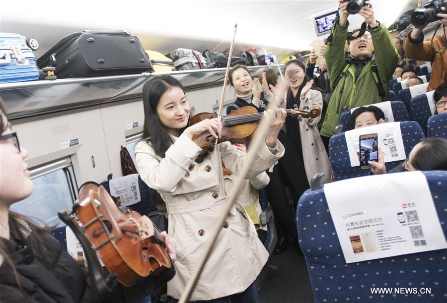 Students from the School of Music of Central China Normal University play violin for passengers on high-speed train G77 from Wuhan, capital of central China's Hubei Province, to Shenzhen, south China's Guangdong Province, Jan. 19, 2017. (Xinhua/Xiao Yijiu) 