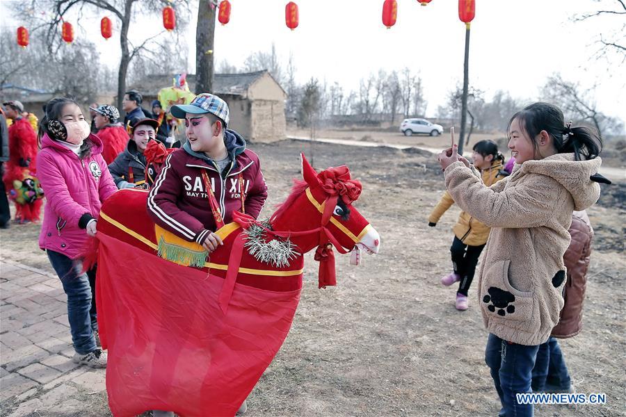 A girl takes photos of a young performer during a folk art performance in Jiulong Village, Pingliang City, northwest China's Gansu Province, Jan. 20, 2017. Local villagers held a folk art performance to celebrate Xiaonian, which falls on Friday this year and marks the start of the countdown to Spring Festival. (Xinhua/Yang Xin) 