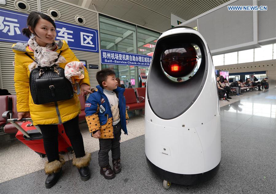 Passengers look at a patrol robot at the Zhengzhou East Railway Station in Zhengzhou, capital of central China's Henan Province, Feb. 15, 2017.