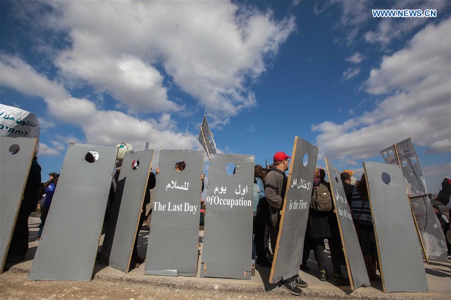 Israeli and Palestinian members of the 'Combatants For Peace' association hold placards representing Israel's controversial separation barrier during a protest against the Israeli barrier near the West Bank city of Bethlehem, on Feb. 17, 2017.