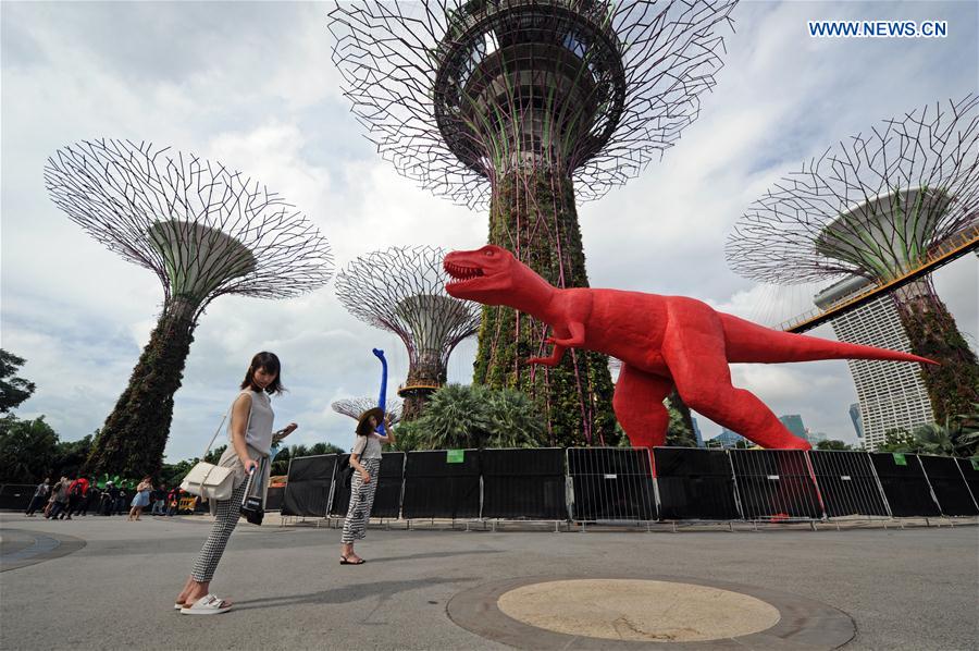 Tourists take photos of a dinosaur statue for the Children's Festival in the Supertree Grove at Singapore's Gardens by the Bay on Feb. 28, 2017. 