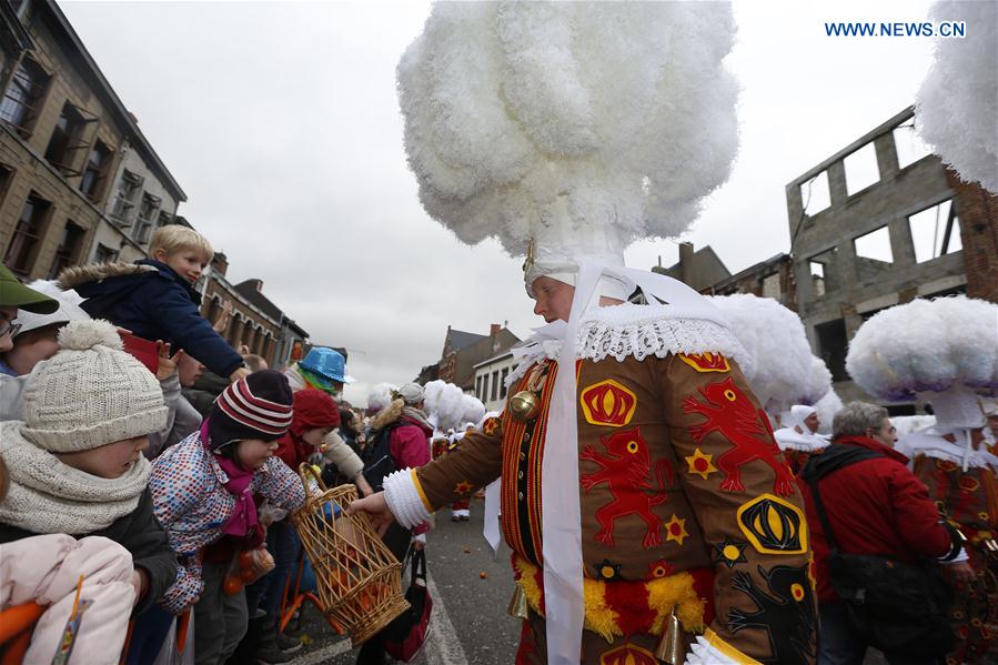'Gilles' wearing hats adorned with huge white ostrich feather plumes march and hold oranges symbolizing the coming Spring, in Binche, Belgium, on Feb. 28, 2017.
