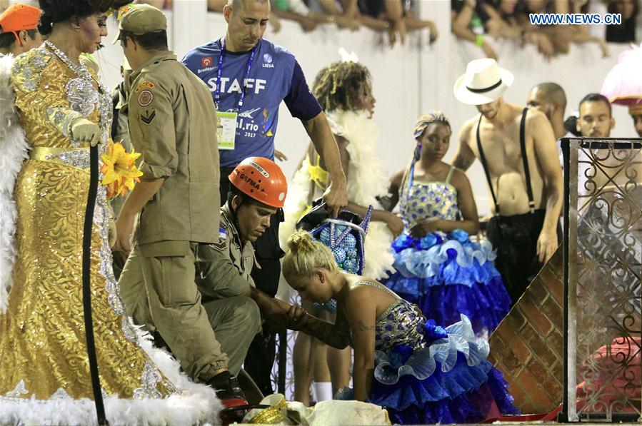 A rescuer helps a woman after the collapse of the top of an allegorical car of the samba school Unidos da Tijuca during the Carnival parade as it advanced through the Marques de Sapucai Avenue, in downtown Rio de Janeiro, Brazil, on Feb. 28, 2017.