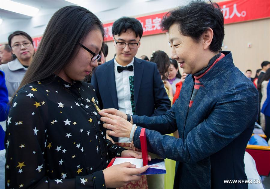 Teacher Su Qing (1st R) awards a medal for a student at the adult ceremony for 18-year-old senior students in high school in Hohhot, capital of north China's Inner Mongolia Autonomous Region, March 7, 2017. (Xinhua/Ding Genhou) 