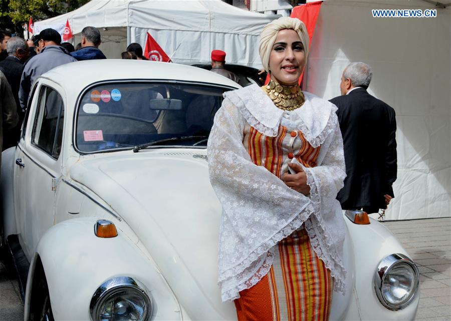 A woman stands in front of a vintage car during a traditional industry show to celebrate the Day of Tradition Industry at the old town in Tunis, Tunisia, on March 12, 2017. 