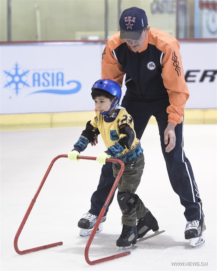 Photo taken on March 4, 2017 shows Jiang Xingyu (L) learning skating from his Russian coach Vsevolod Popov of Binglong International Skating Club at a skating rink in a shopping mall in Wuhan, central China's Hubei Province. Keeping up a sound and steady pace of development, the Chinese sports industry was booming in 2016. The National Fitness Program (2016-2020) and the 13th Five-year Plan on the Sports Industry were both issued in 2016 to offer a clear direction for China's national strategy of ensuring public fitness and the development of the sports industry. China's General Administration of Sport, jointly with many other national governmental departments, also published policies and plans on winter sports. It released a plan on Nov. 2, 2016 to speed up the construction of winter sports infrastructure, aiming to build at least 500 skating rinks before the 2022 Winter Olympic Games. Four of six ski resorts are built in Shennongjia. During season 2016-2017, Shennongjia Ski resort accommodated more than 120,000 tourists, up 35 percent from 2015. A winter sports training base is planned to construct in Shennongjia for traning professional athletes. Around 2,000 people regularly participate in skating sports at five rinks in Wuhan, capital of Hubei Province every year. (Xinhua/Xiao Yijiu)