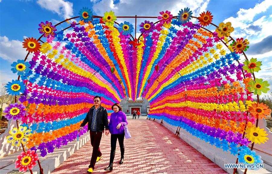 Tourists walk on a road decorated with colorful pinwheels at a Pinwheel and Kite Festival in Tangshan, north China's Hebei Province, March 27, 2017. 