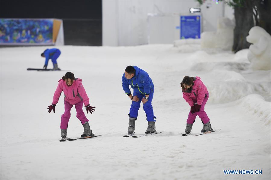 A coach (C) teaches two gils to ski in 'Snow Kingdom of Three Bears' in Changsha, capital of central China's Hunan Province, on March 8, 2017.