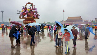 Tourists carrying umbrellas visit Tian'anmen Square