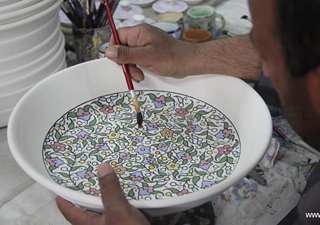 Palestinian workers paint on ceramic article in Hebron