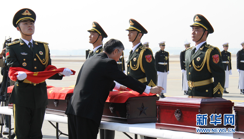 中国驻韩大使邱国洪（前左）为中国人民志愿军烈士遗骸棺椁覆盖中国国旗。