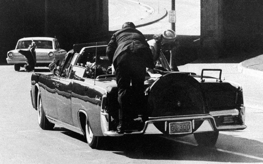 7.1963年11月22日12：30左右，肯尼迪总统在被枪击后倒在了车后座上，第一夫人杰奎琳-肯尼迪俯身在总统边，特工克林特-希尔试图将她推回座位上，以防其掉出车外。