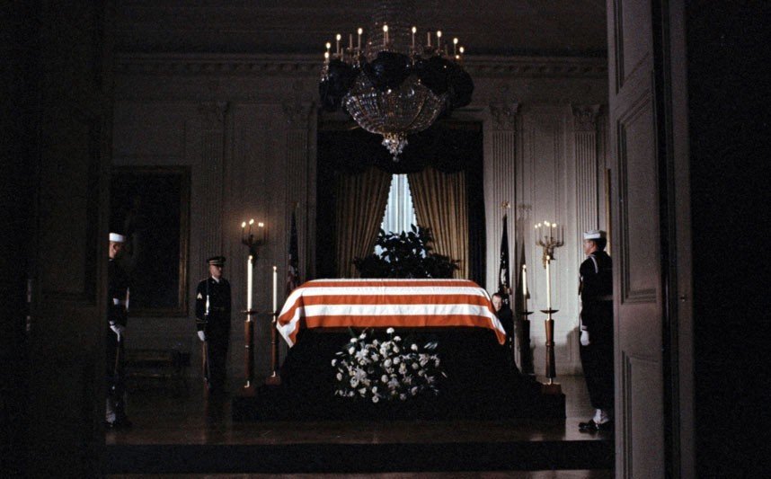 15.1963年11月23日，国旗覆盖下的肯尼迪总统灵柩放置在白宫东厢内。第一夫人希望灵柩置于东厢，因此处为当年林肯遇刺后棺柩所放位置。